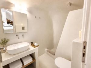 a white bathroom with a sink and a mirror at Fira Centrum White in Fira +25 photos