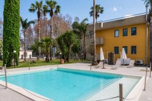 a swimming pool in front of a building with palm trees at Oasi Park Hotel in Mascali