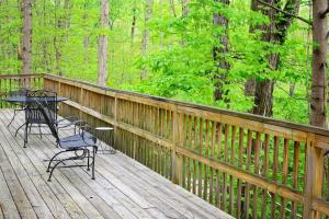 a wooden deck with a table and chairs on it at Tree-Top Chalet in Logan +15 photos