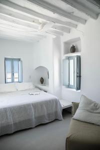 a white bedroom with a bed and a couch at DYO Tinos in Triandáros