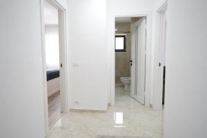 a hallway with white walls and a bathroom with a toilet at Apartament Ultracentral NICOL in Curtea de Argeş +10 photos