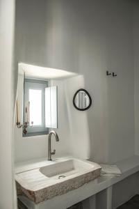 a white bathroom with a sink and a mirror at DYO Tinos in Triandáros