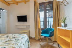 a bedroom with a bed and a blue chair at Hostal Santa Catalina in Conil de la Frontera +98 photos