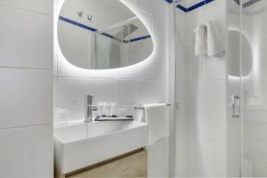 a white bathroom with a sink and a mirror at Hostal Santa Catalina in Conil de la Frontera