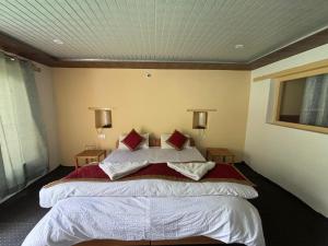 a bedroom with a large bed with red pillows at Saser Camp in Nubra