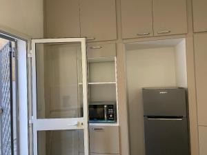 a small kitchen with a microwave and a refrigerator at Chez Brahim in Ariana