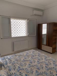 a bedroom with a large bed and two windows at Chez Brahim in Ariana