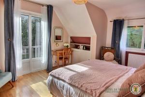 a bedroom with a bed and a desk and windows at L'orée du bois in Ploumagoar