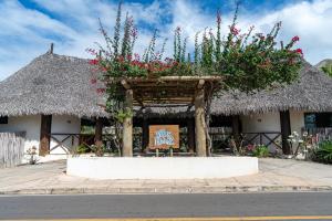 a building with flowers and a sign in front of it at Villas BobZ in Barrinha