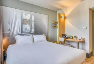 a bedroom with a large white bed and a desk at B&B HOTEL Bordeaux Sud Mios 3 étoiles in Mios