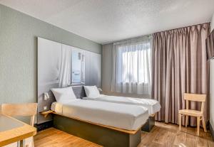 a hotel room with a bed and a window at B&B HOTEL Bordeaux Sud Mios 3 étoiles in Mios