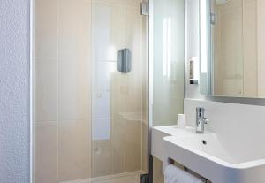 a bathroom with a shower and a sink and a mirror at B&B HOTEL Bordeaux Sud Mios 3 étoiles in Mios
