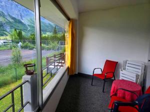 a room with two red chairs and a window at Schlossli-Le Petit Chateau in Leukerbad