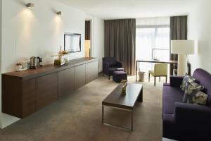 a living room with a couch and chairs and a tv at Atlantic Congress Hotel Essen, WorldHotels Elite in Essen