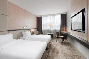 a hotel room with two beds and a desk at Radisson Blu Szczecin in Szczecin