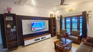 a living room with a large tv and a couch at Greenview Homestay in Sakleshpur