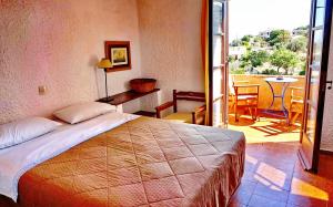 a bedroom with a bed and a balcony with a table at Vagia Traditional, Aegina Island in Vaia