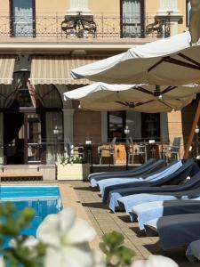 Eine Reihe von Betten mit Sonnenschirmen neben einem Pool in der Unterkunft Hotel Otrada in Odessa