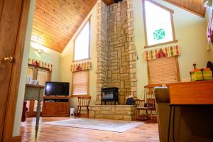 a living room with a stone fireplace and a television at Hemlock Hideaway in South Bloomingville +15 photos