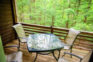 a table and chairs on a porch with a view of the woods at Hemlock Hideaway in South Bloomingville