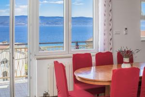 a dining room with red chairs and a table and windows at Azra Apartments in Duće