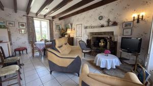 a living room with chairs and a tv and a fireplace at Le gîte du porche in Saint-Georges-lès-Baillargeaux