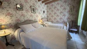 a bedroom with two beds and floral wallpaper at Le gîte du porche in Saint-Georges-lès-Baillargeaux