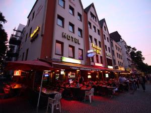 eine Gruppe von Personen, die vor einem Gebäude an Tischen sitzen in der Unterkunft Hotel Kunibert der Fiese - Superior in Köln