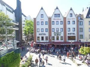 a group of people walking in a street with buildings at Hotel Kunibert der Fiese - Superior in Cologne