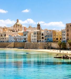 a view of a beach with buildings in the background at Torrearsa 17 in Trapani
