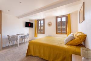 a bedroom with a yellow bed and a table at Suite du Soleil - Studio - Hypercentre in Narbonne