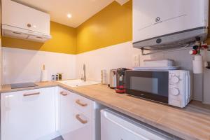 a kitchen with a microwave on a wooden counter at Suite du Soleil - Studio - Hypercentre in Narbonne