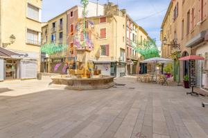 a fountain in the middle of a street with buildings at Suite du Soleil - Studio - Hypercentre in Narbonne +6 photos