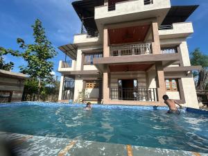 two people in a swimming pool in front of a house at Vasant Vihar Farm House in Silvassa