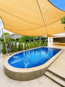 a large swimming pool with a large umbrella at กัลยา รีสอร์ท in Ban Bang Saen (1)