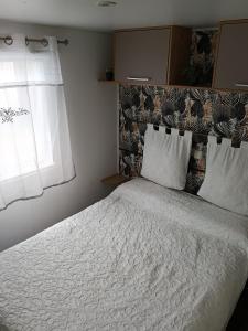 a bedroom with a bed with white sheets and a window at Le Deauville in Le Grau-dʼAgde