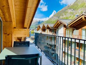 a balcony with a table and chairs and mountains at Peaky Riders Self Check-in Hotel in Zermatt