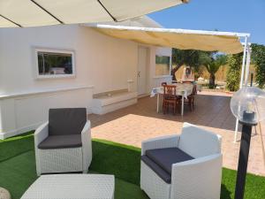 a patio with chairs and a table and an umbrella at DolceApulia Country House in Conversano