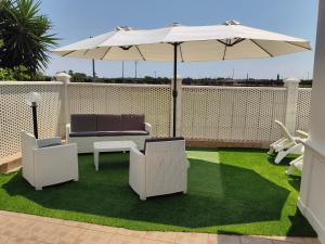 a patio with two chairs and an umbrella and grass at DolceApulia Country House in Conversano