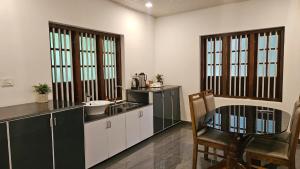 a kitchen with a sink and a table and a table and chairs at Villa Terra, Spacious 2BR Villa in Kannur