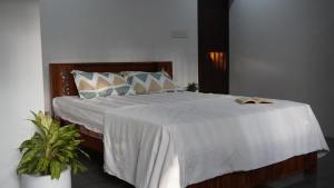 a bedroom with a large bed with white sheets and pillows at Villa Terra, Spacious 2BR Villa in Kannur