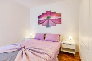 a bedroom with a purple bed and a painting on the wall at Apartman Doris in Lovran