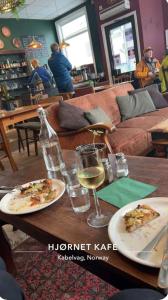 a table with two plates of pizza and a glass of wine at Rosahuset in Kabelvåg