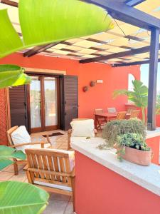 a patio with chairs and tables and an orange wall at Villaelena Salento Mare in Marittima