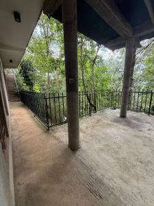 an empty porch with a black fence and trees at Sunlee Aviana in Bandarawela