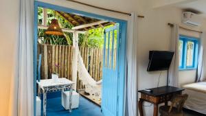 a room with a door leading to a porch with a hammock at Pousada Caraíva in Caraíva