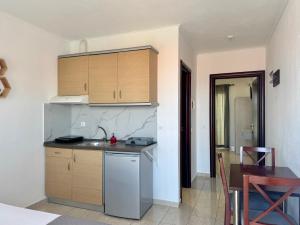 a kitchen with wooden cabinets and a table in a room at Melis Studios in Kallithea Halkidikis