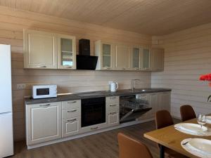 a kitchen with white cabinets and a microwave and a table at Тиха Хвиля in Gribovka +37 photos