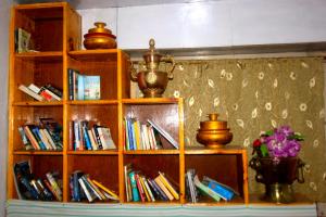un estante de libros lleno de libros y un jarrón de flores en Himalayan Lodge, en Nāmche Bāzār