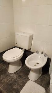 a bathroom with a white toilet and a sink at Cabañas Elementos in Huerta Grande